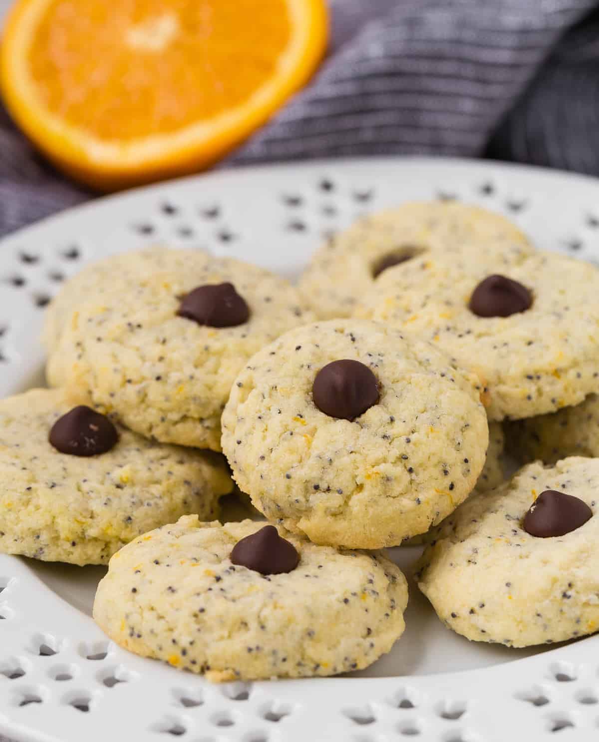 Cookies on a decorative white plate with an orange half in the background.