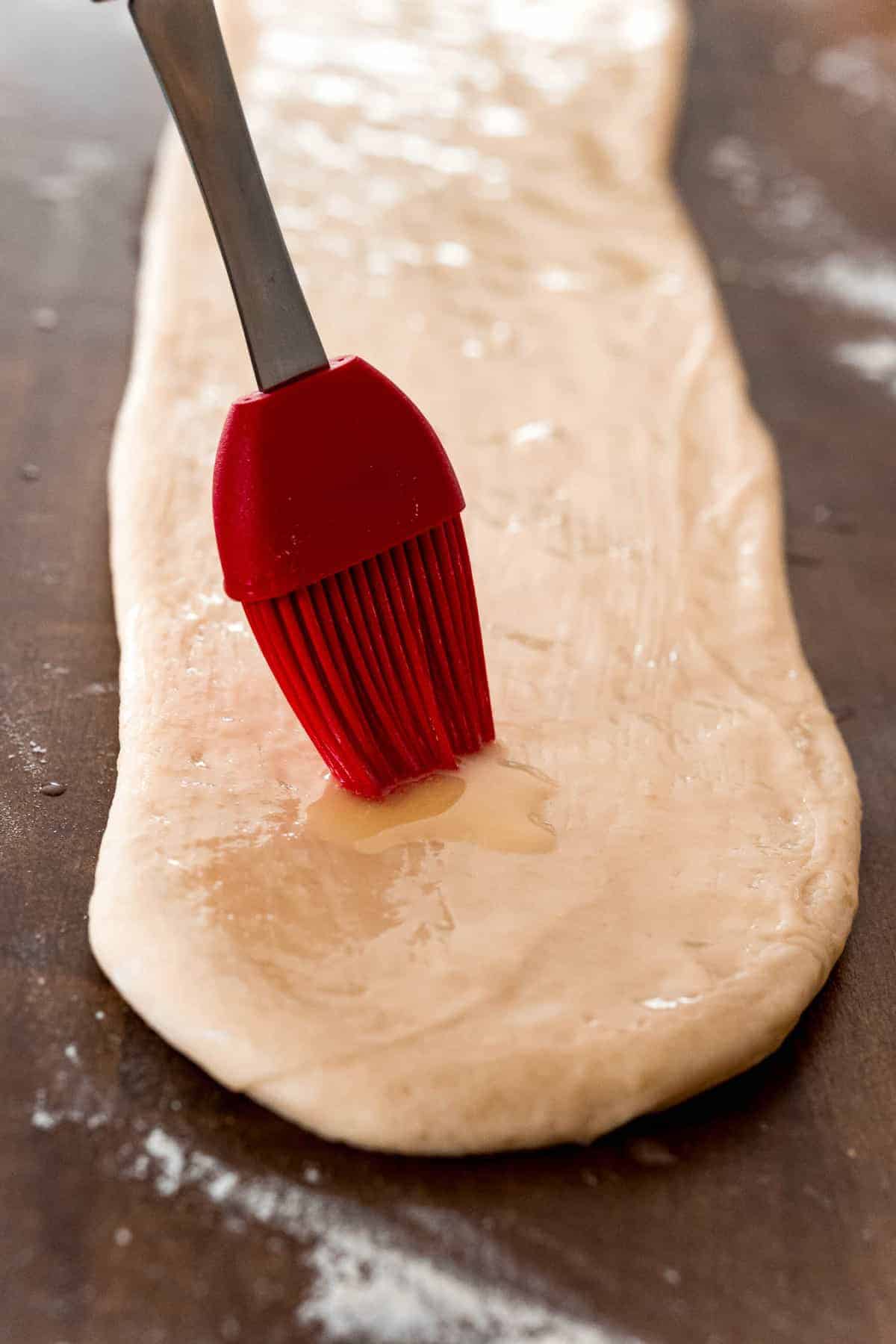 Butter being brushed on yeasted dough.