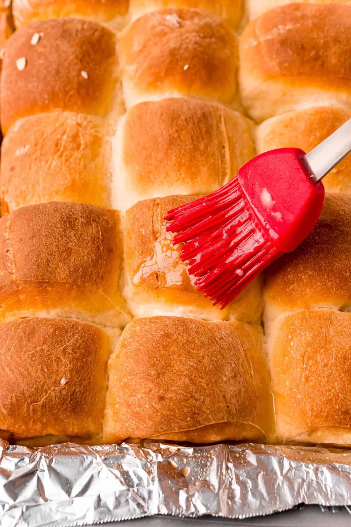 Freshly baked rolls being brushed with butter.