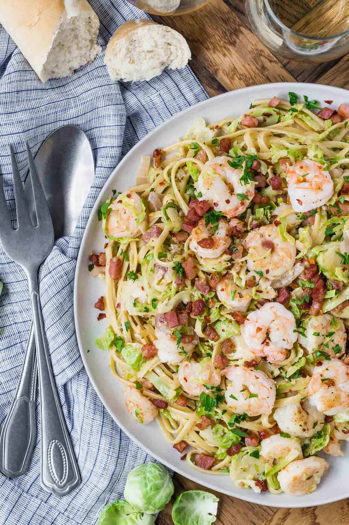 Overhead view of a platter of pasta, with serving utensils next to it.