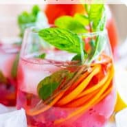 Brightly colored red drink with pomegranate arils, citrus slices, and fresh mint. Text overlay reads "sparkling pomegranate punch"