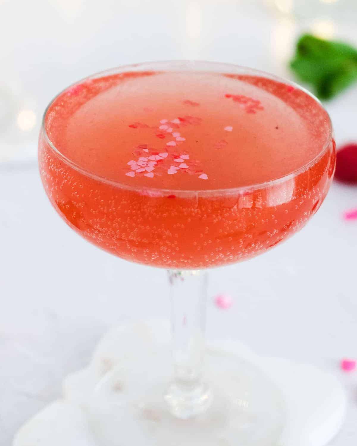 Close up of a sparkling pink drink with heart sprinkles.