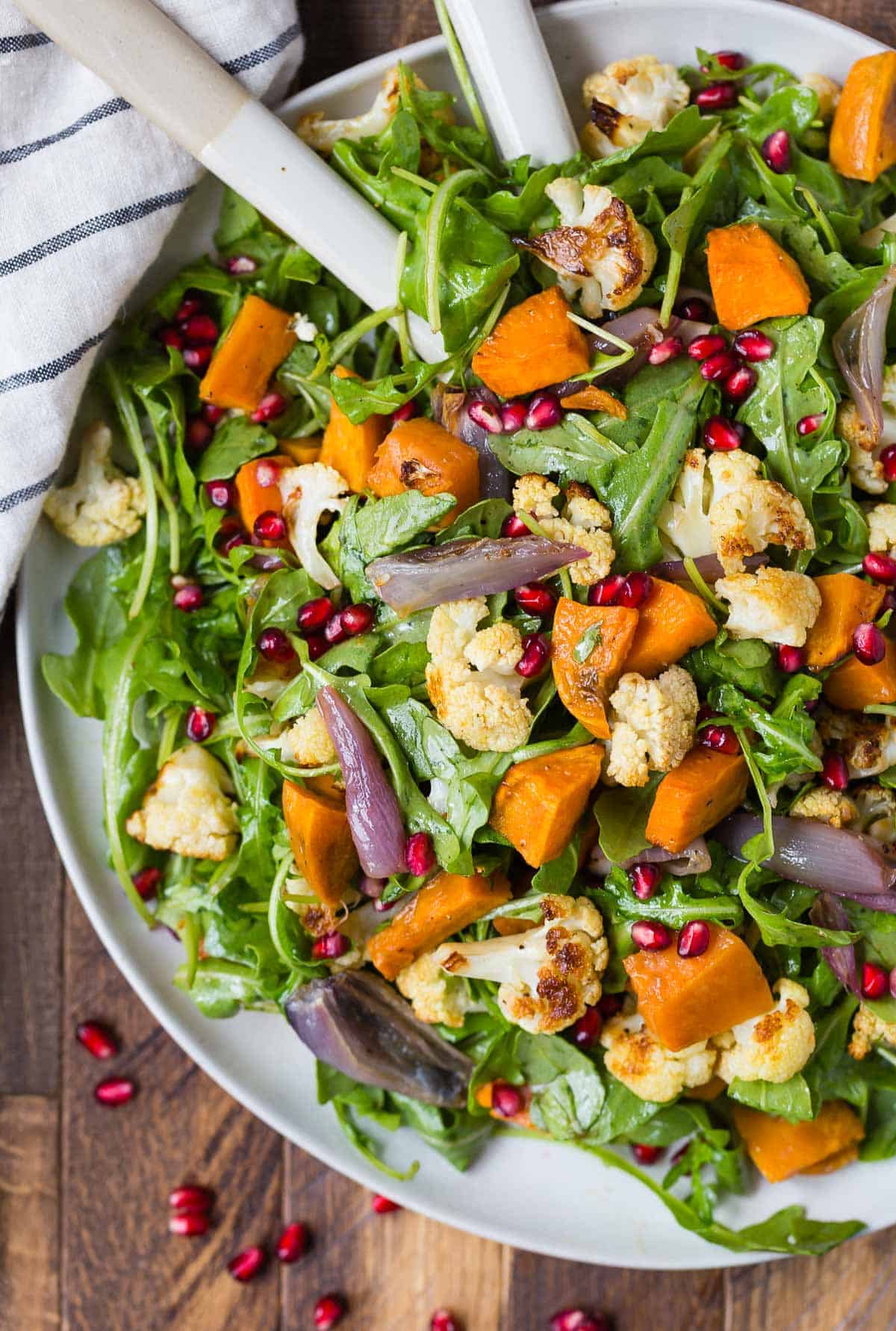 Colorful salad with arugula, cauliflower, sweet potatoes, and pomegranates.