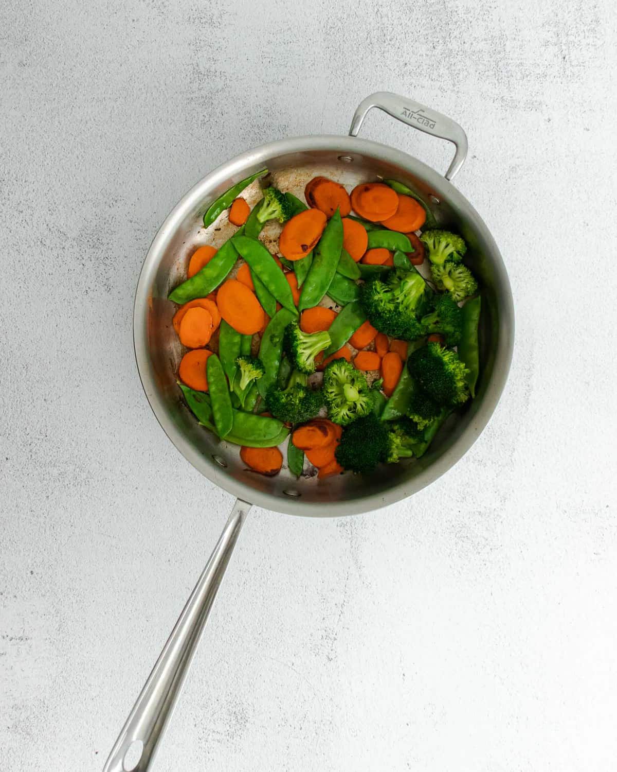 Stir fry vegetables in a pan.