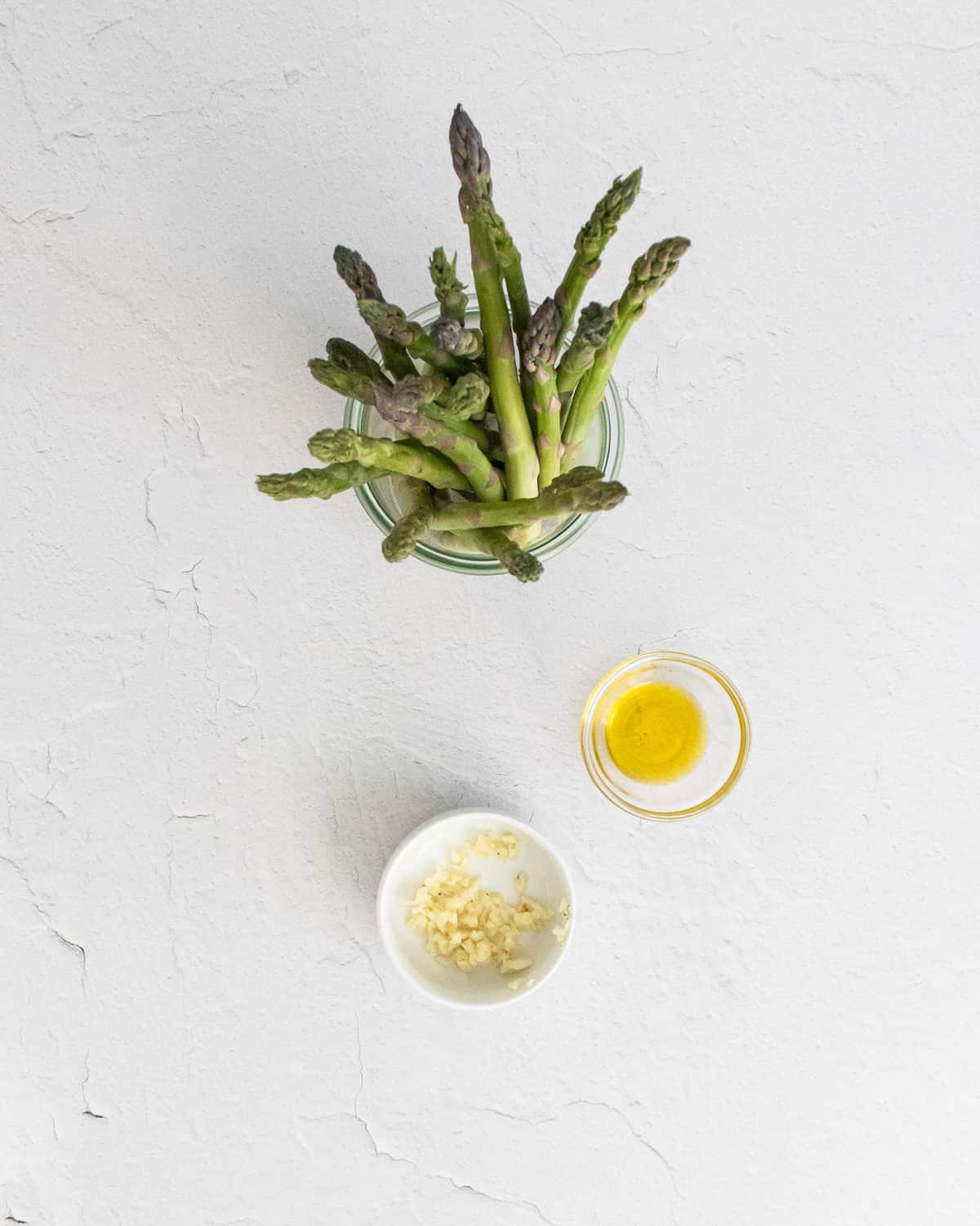Ingredients needed for roasted asparagus, on a white background.