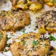 Potatoes on a sheet pan, text overlay reads "garlic parmesan smashed potatoes"