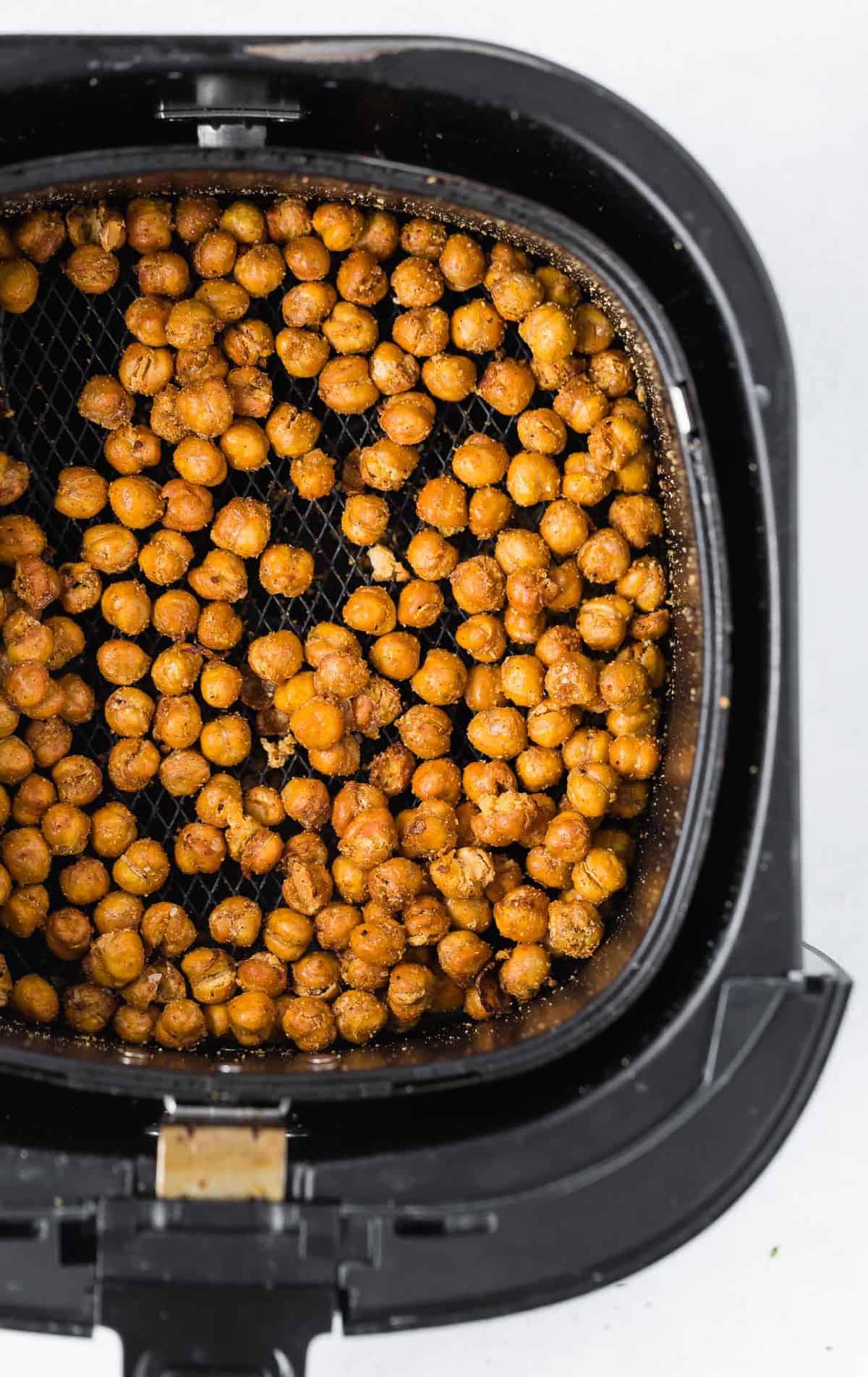 Overhead view of crispy chickpeas in a black air fryer basket.