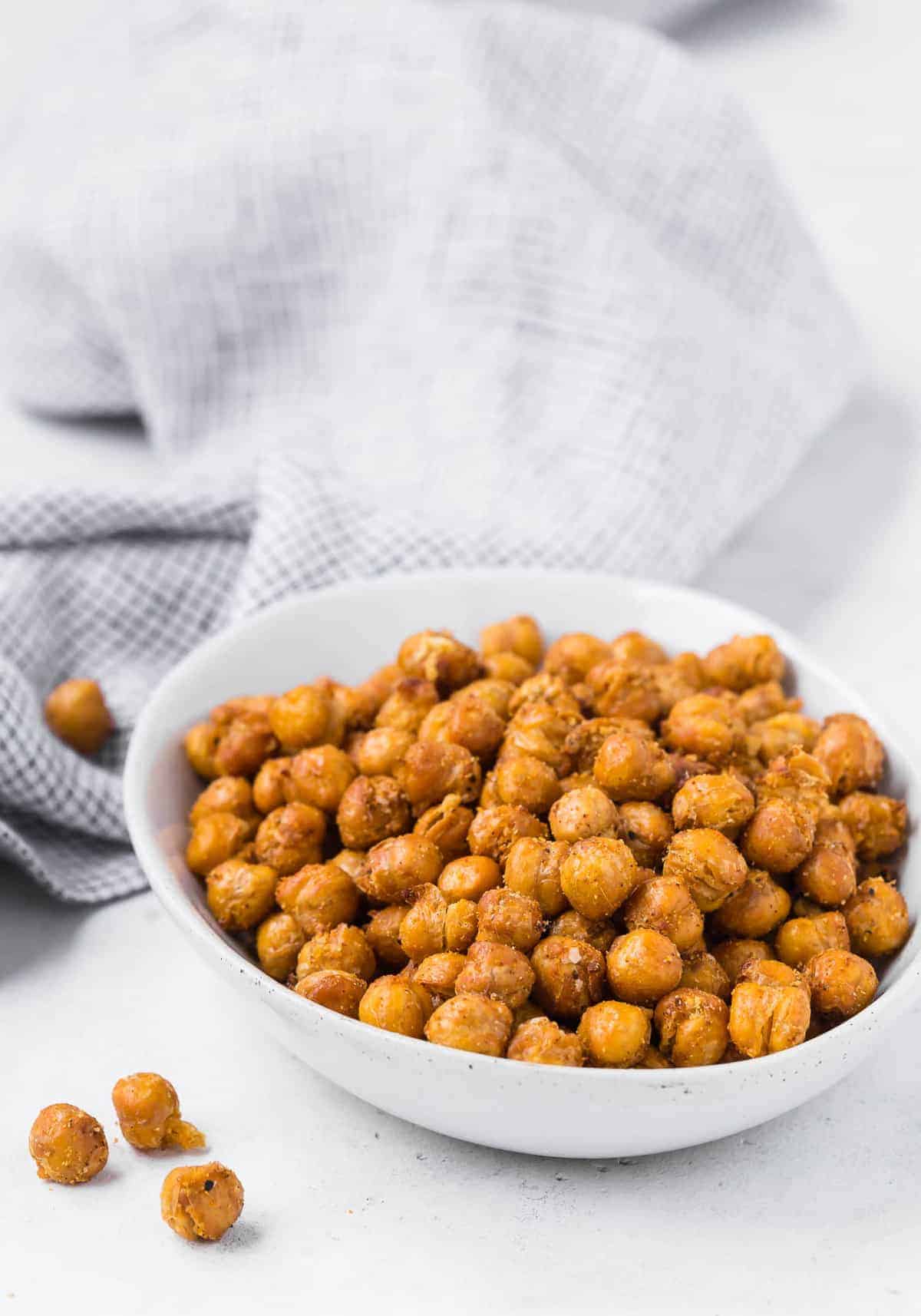 A bowl of chickpeas that have been air fried, black and white linen in background.