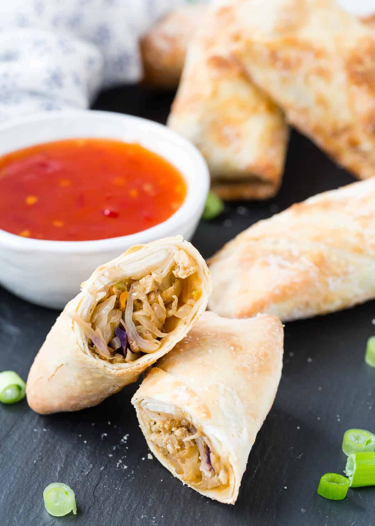 Egg roll cut in half on a black slate surface.