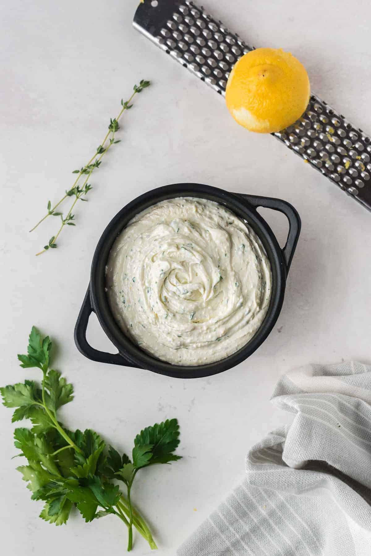 Unbaked goat cheese spread in a black baking dish.