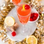 Overhead view of a light red cocktail garnished with lemon and a maraschino cherry.