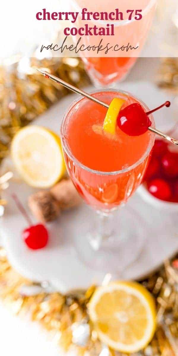 Light red drink garnished with lemon and a cherry. Text overlay reads, "cherry french 75 cocktail, rachelcooks.com"