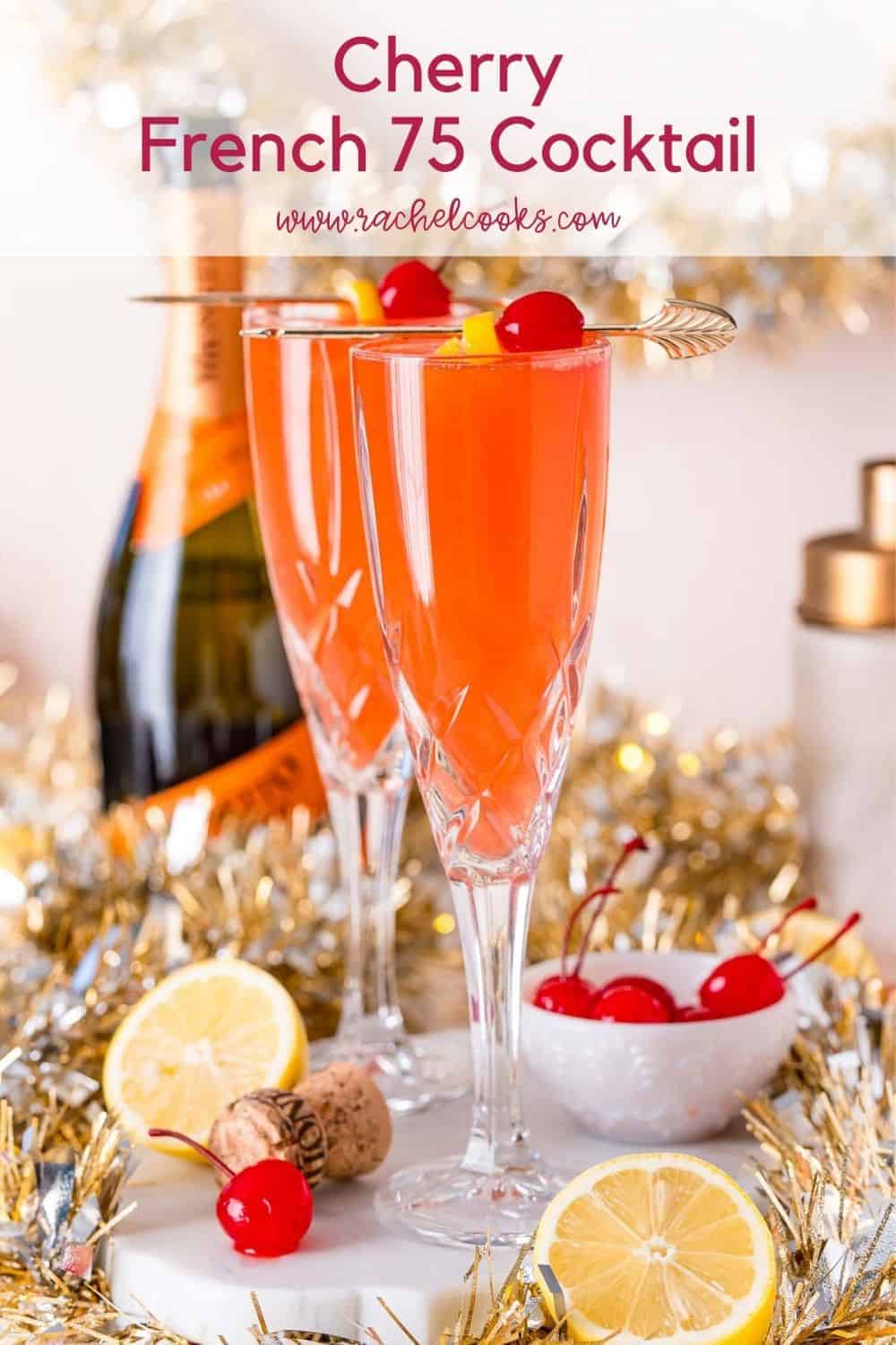 Light red drink garnished with lemon and a cherry. Text overlay reads, "cherry french 75 cocktail, rachelcooks.com"