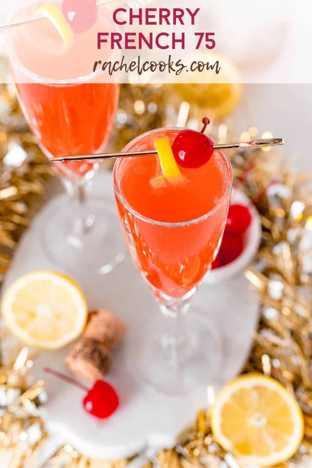 Light red drink garnished with lemon and a cherry. Text overlay reads, "cherry french 75, rachelcooks.com"