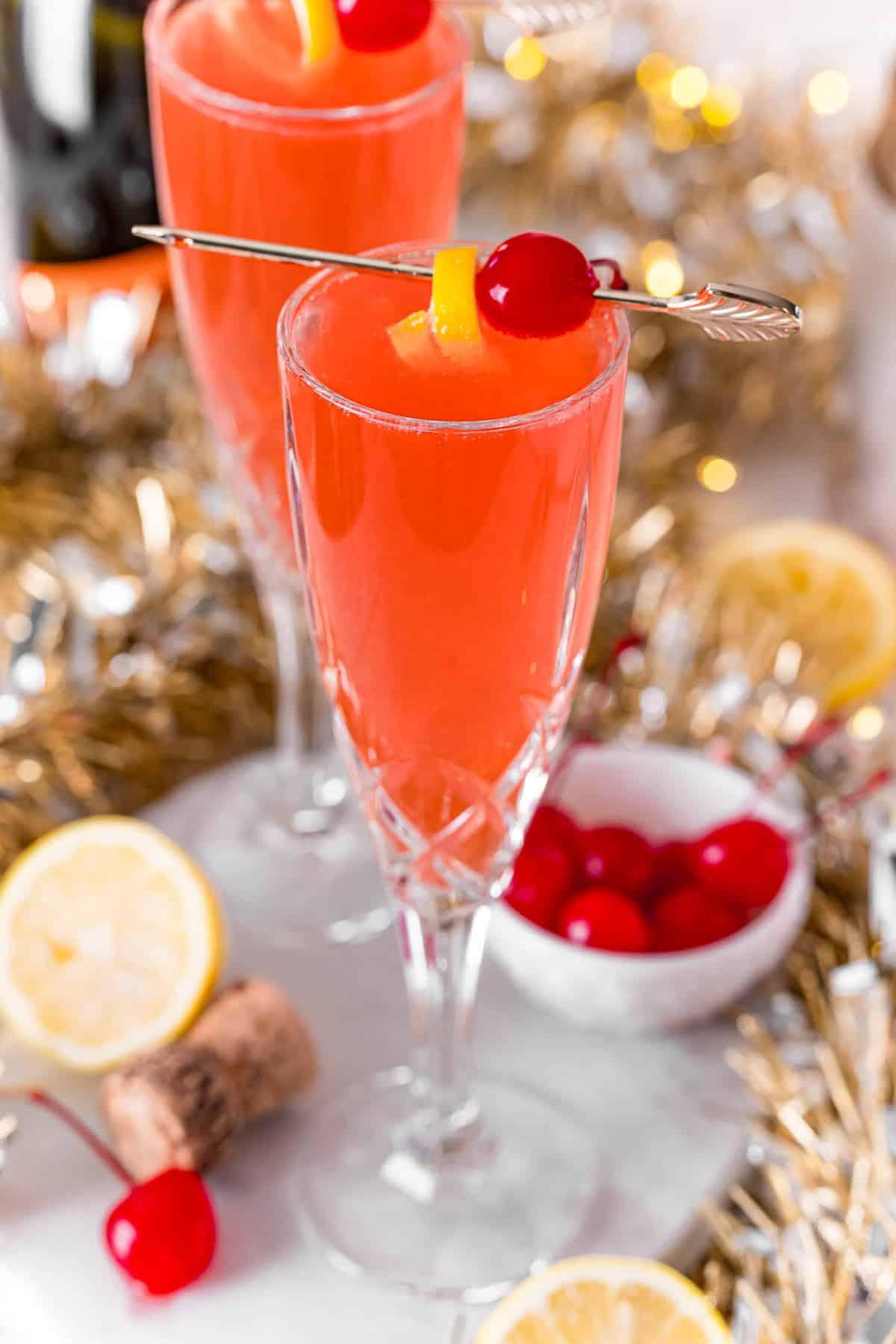 Cherry french 75 garnished with cherry and lemon peel.