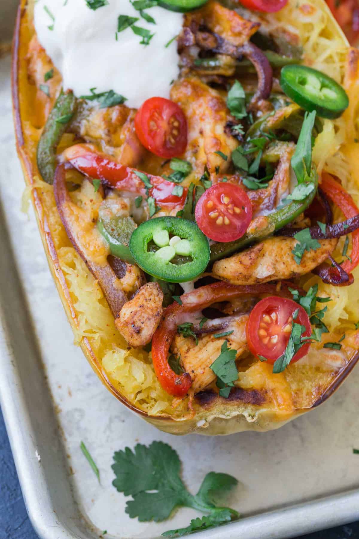 Close up of a spaghetti squash half stuffed with chicken fajita ingredients.