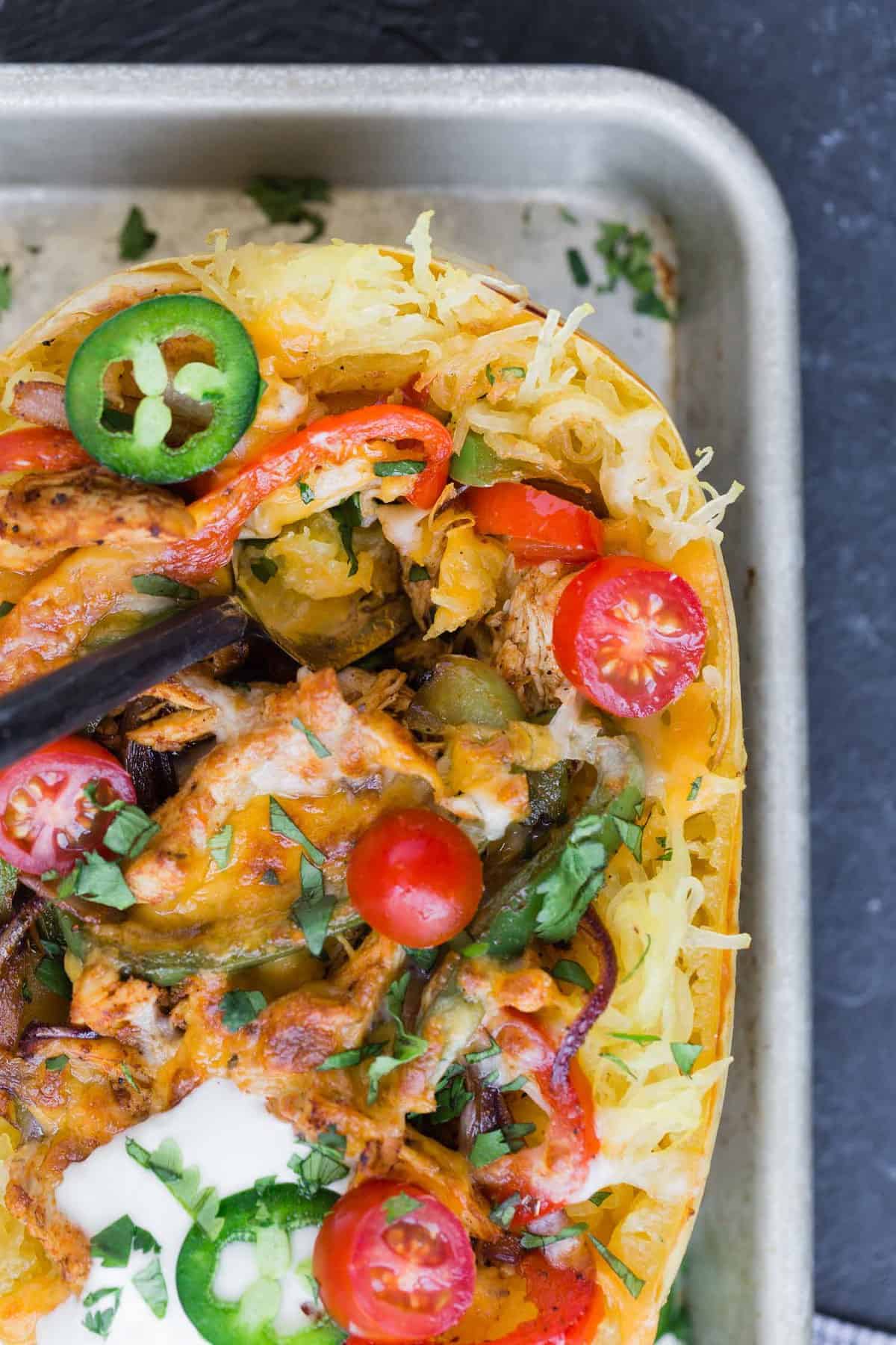 Close up of a chicken fajita stuffed spaghetti squash with toppings.