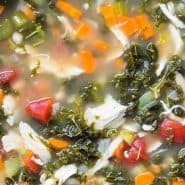 Colorful soup in a black slow cooker, text overlay reads "crockpot chicken and kale soup, rachelcooks.com"