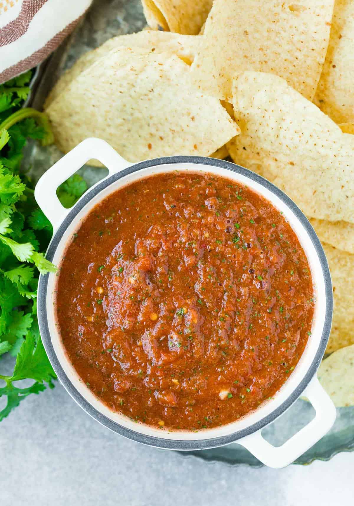 Overhead view of chipotle salsa in a white dish, surrounded by chips.