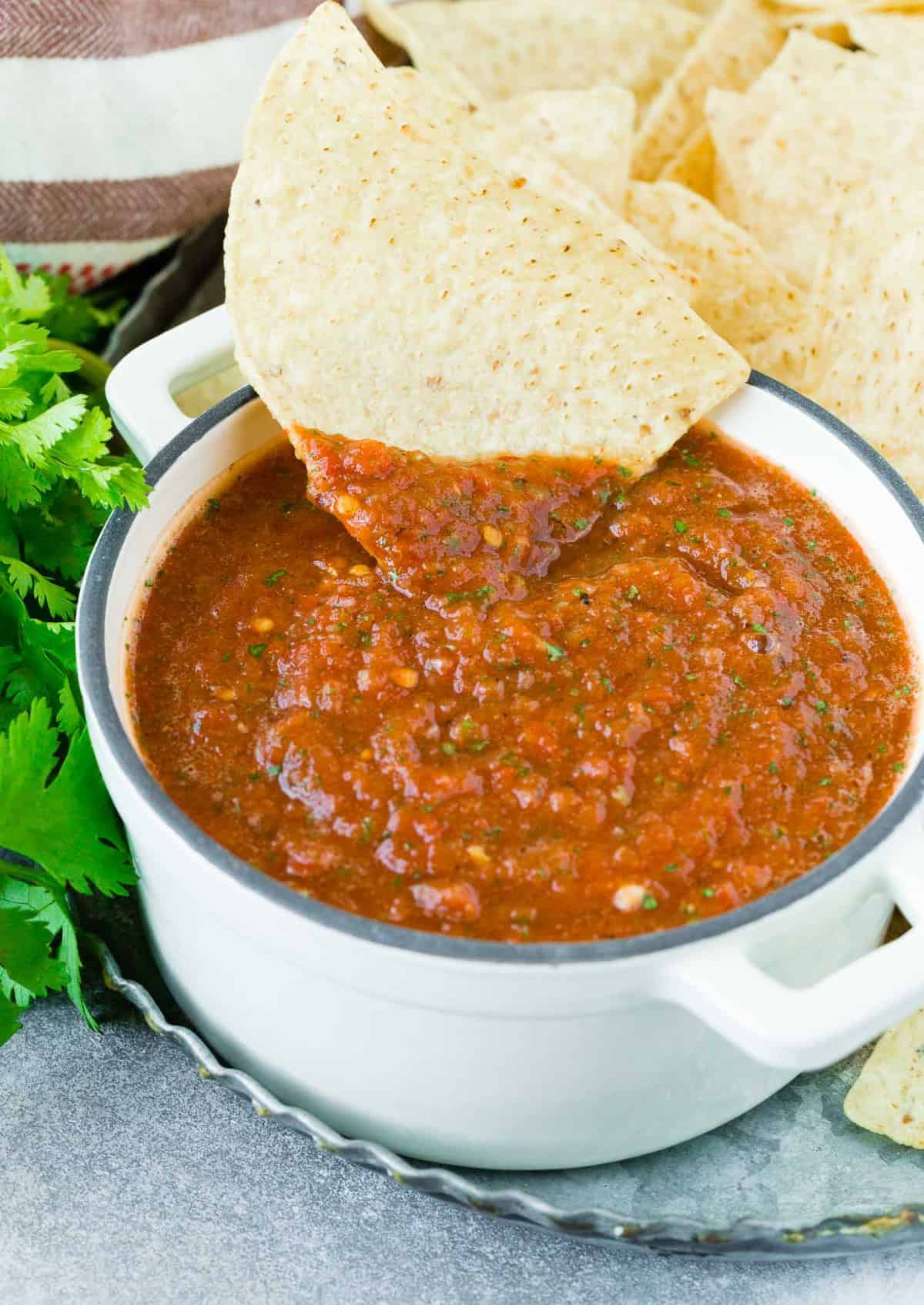 A tortilla chip being dipped in salsa.