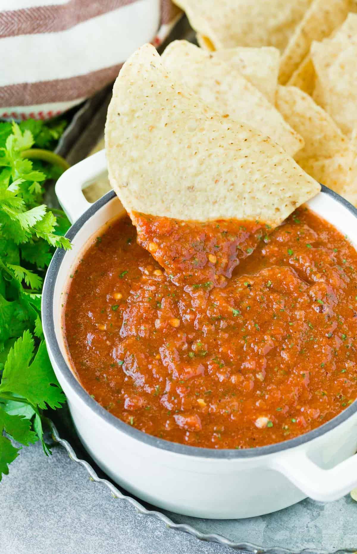 Tortilla chip being dipped into a bowl of salsa.