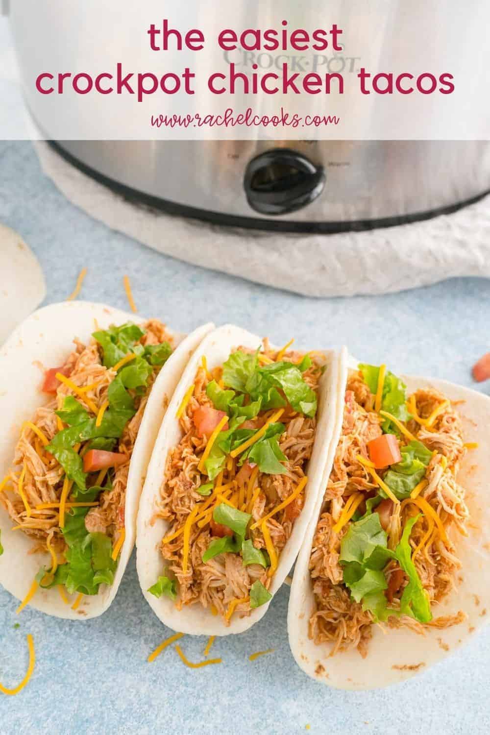 Shredded chicken on a tortilla with cheese, lettuce, and tomatoes. Text overlay reads "the best crockpot chicken tacos"