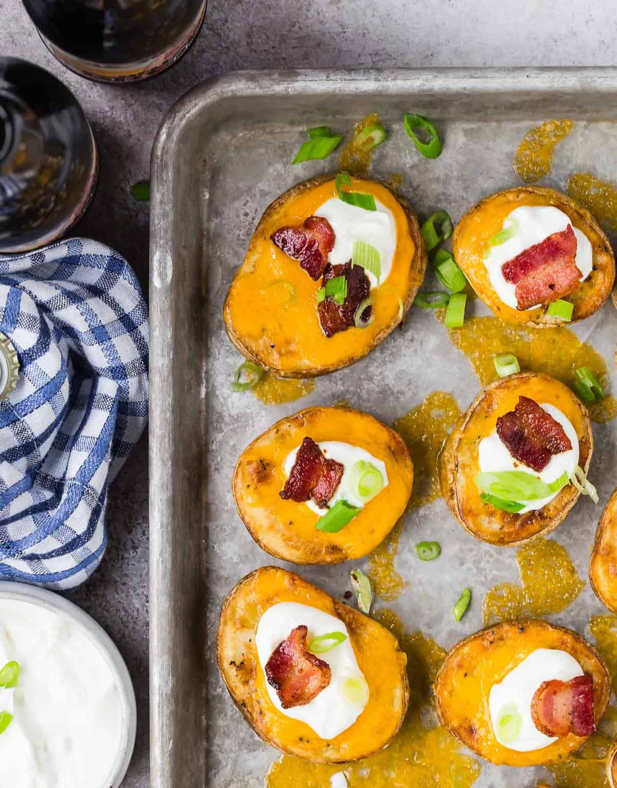 Overhead view of potato slices with toppings on a baking sheet.