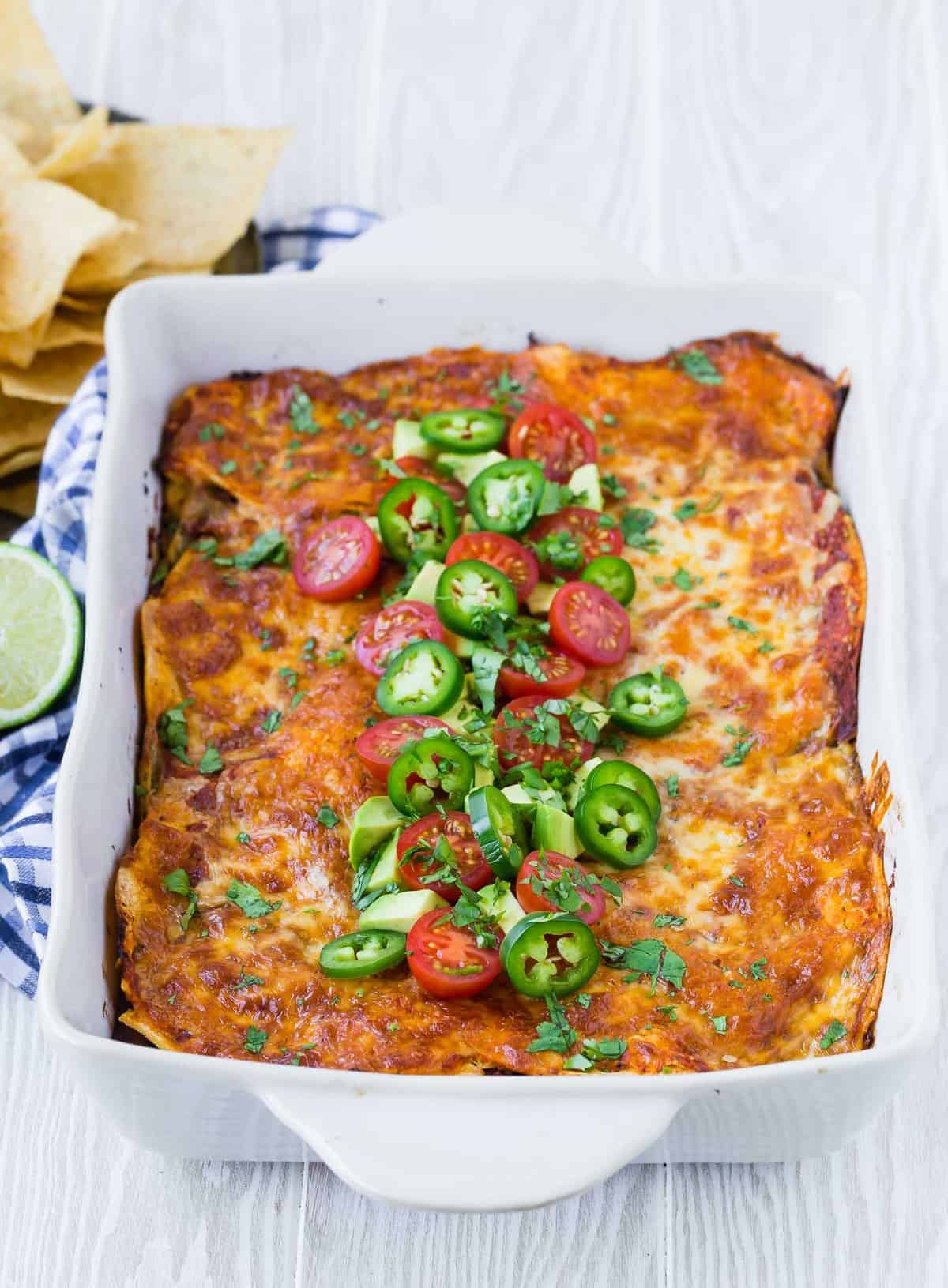 Casserole dish of healthy mexican lasagna with southwestern garnishes.