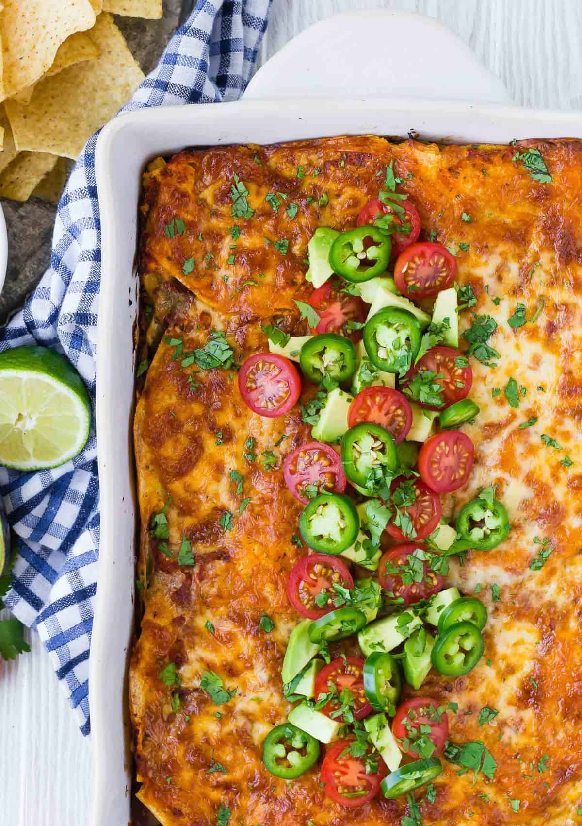 Overhead view of colorful casserole, topped with fresh tomatoes, jalapeno, and avocado.