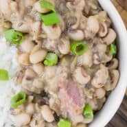 Beans, rice, and ham topped with green onions in small white bowls. Text overlay reads "hoppin' john (black eyed peas & rice), rachelcooks.com"