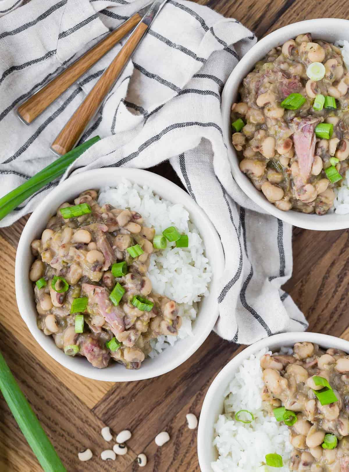 three bowls of hoppin' john on a wooden background