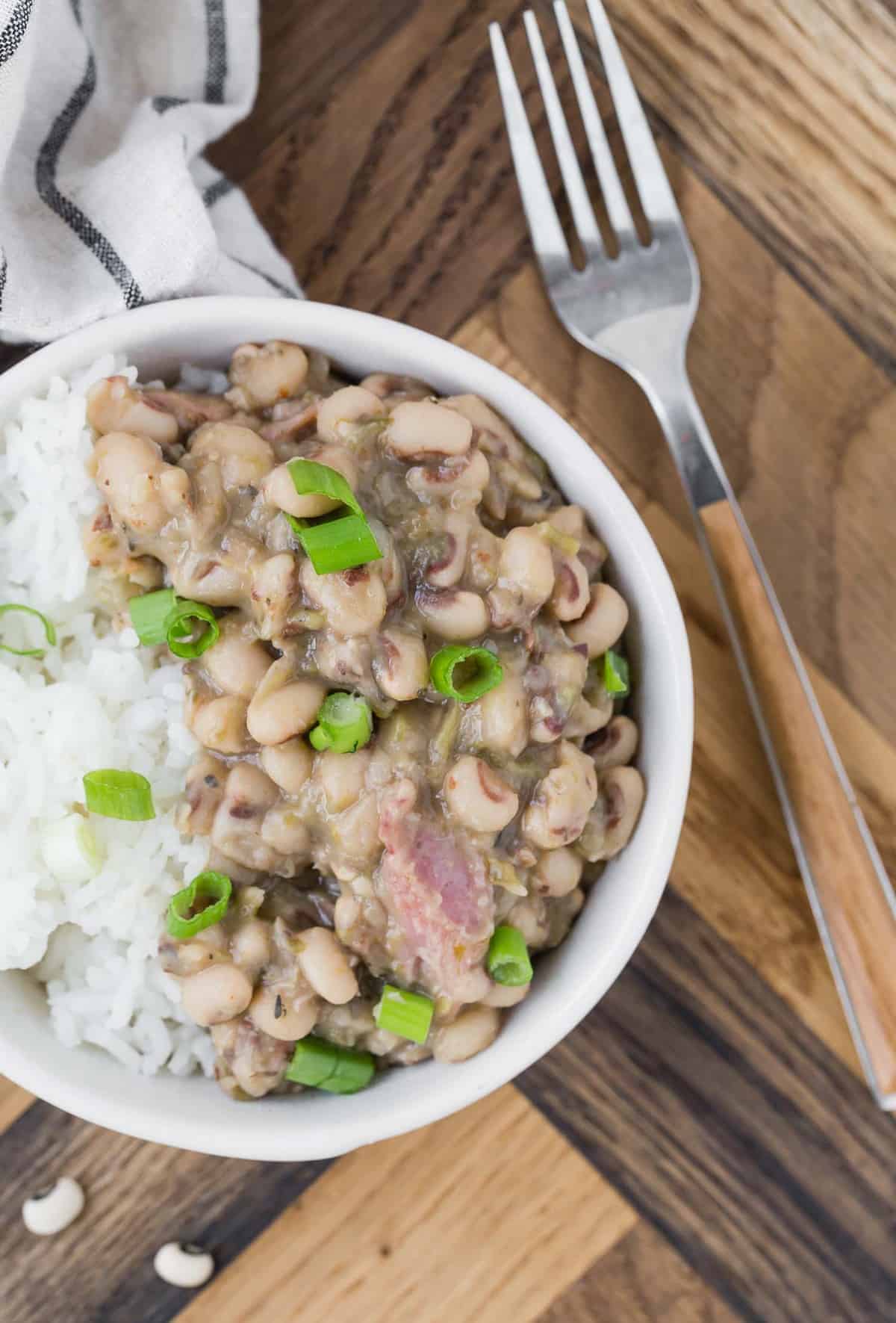 Black eyed peas and ham served over white rice garnished with green onions.