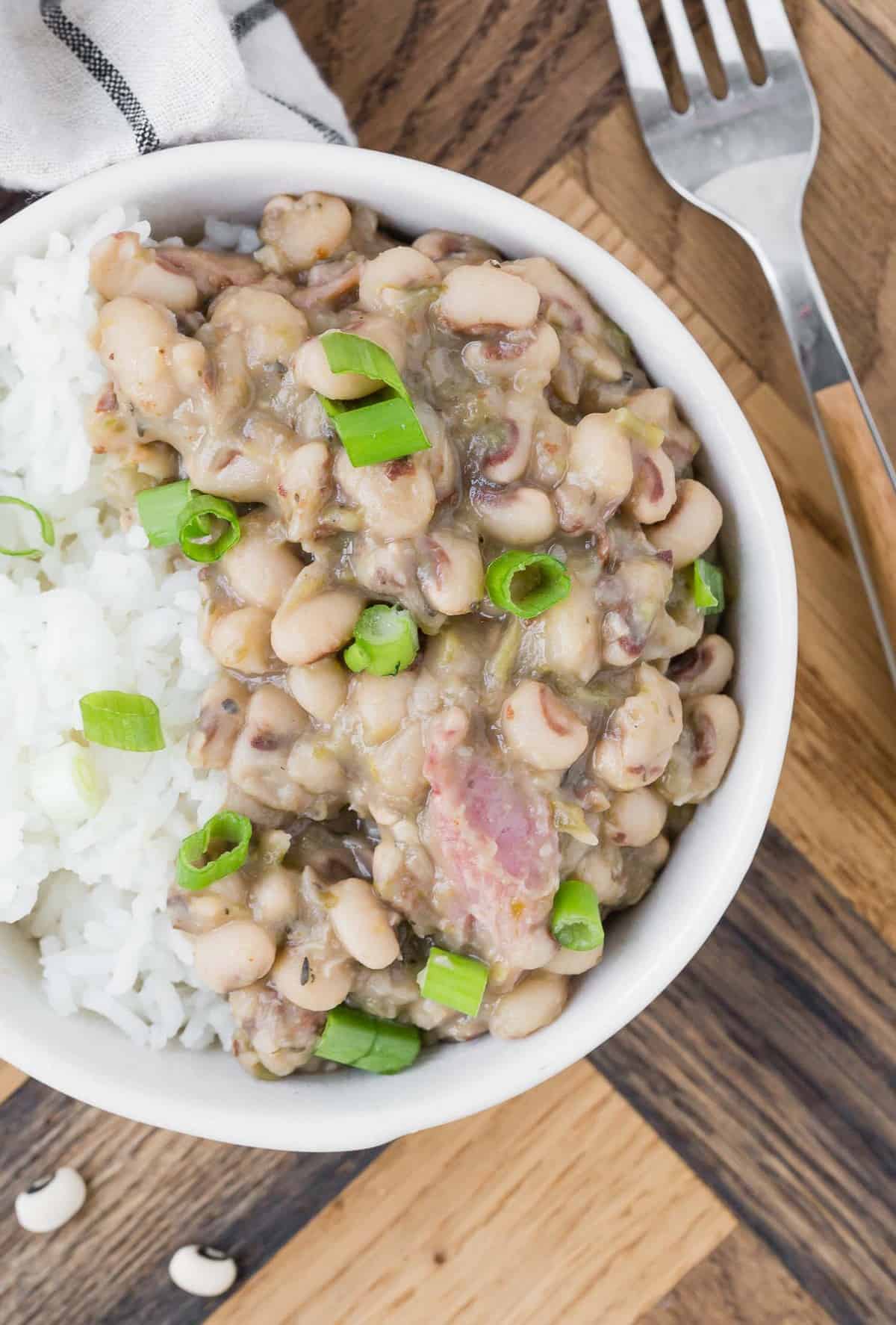 Close up view of stewed black eyed peas, white rice, and green onions.