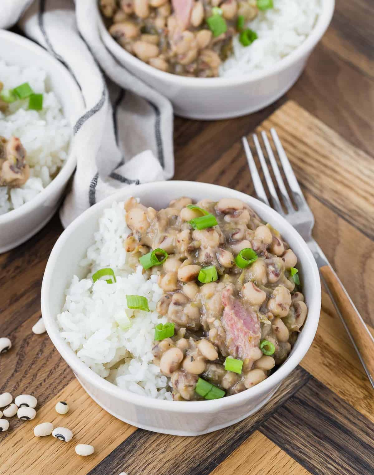 Black eyed peas and rice in a white bowl on a wooden background.