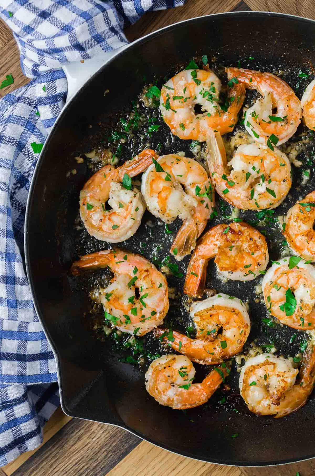 Lemon pepper shrimp in a black skillet.