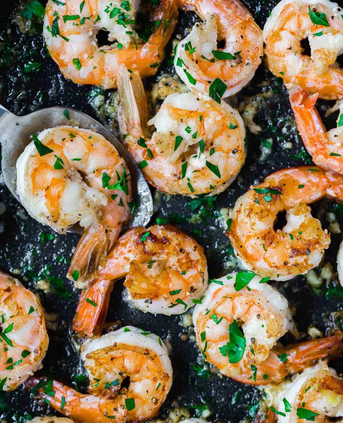 Close up of cooked shrimp in a black skillet.