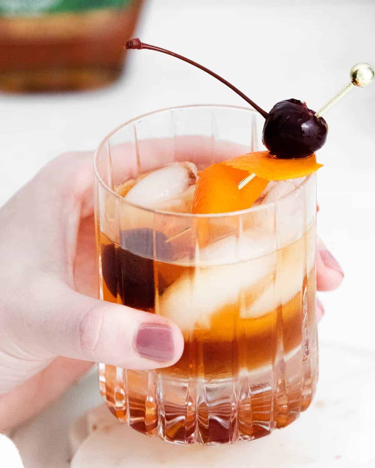 Old fashioned cocktail in a female's hand. 