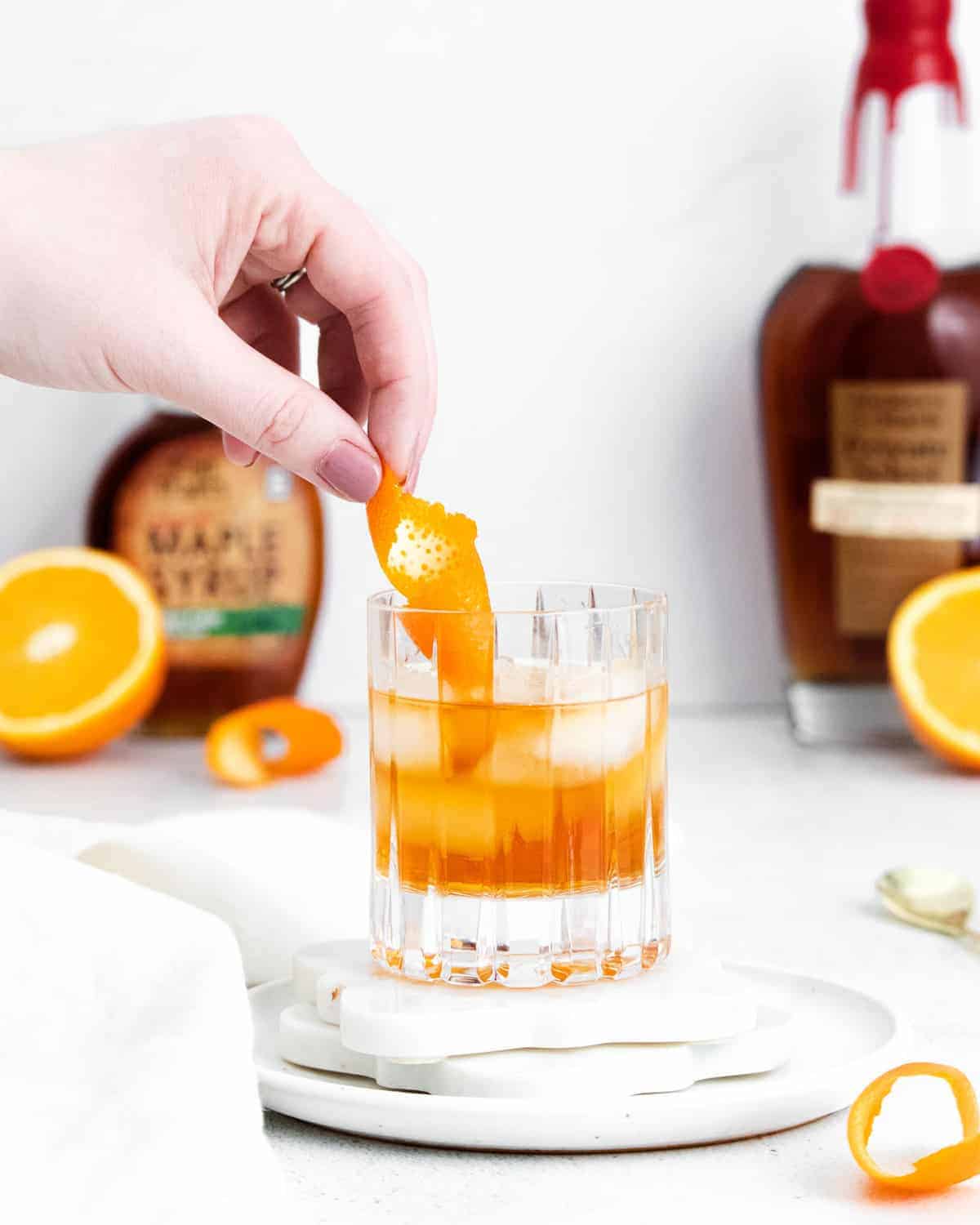 Orange peel being added to an old fashioned cocktail.