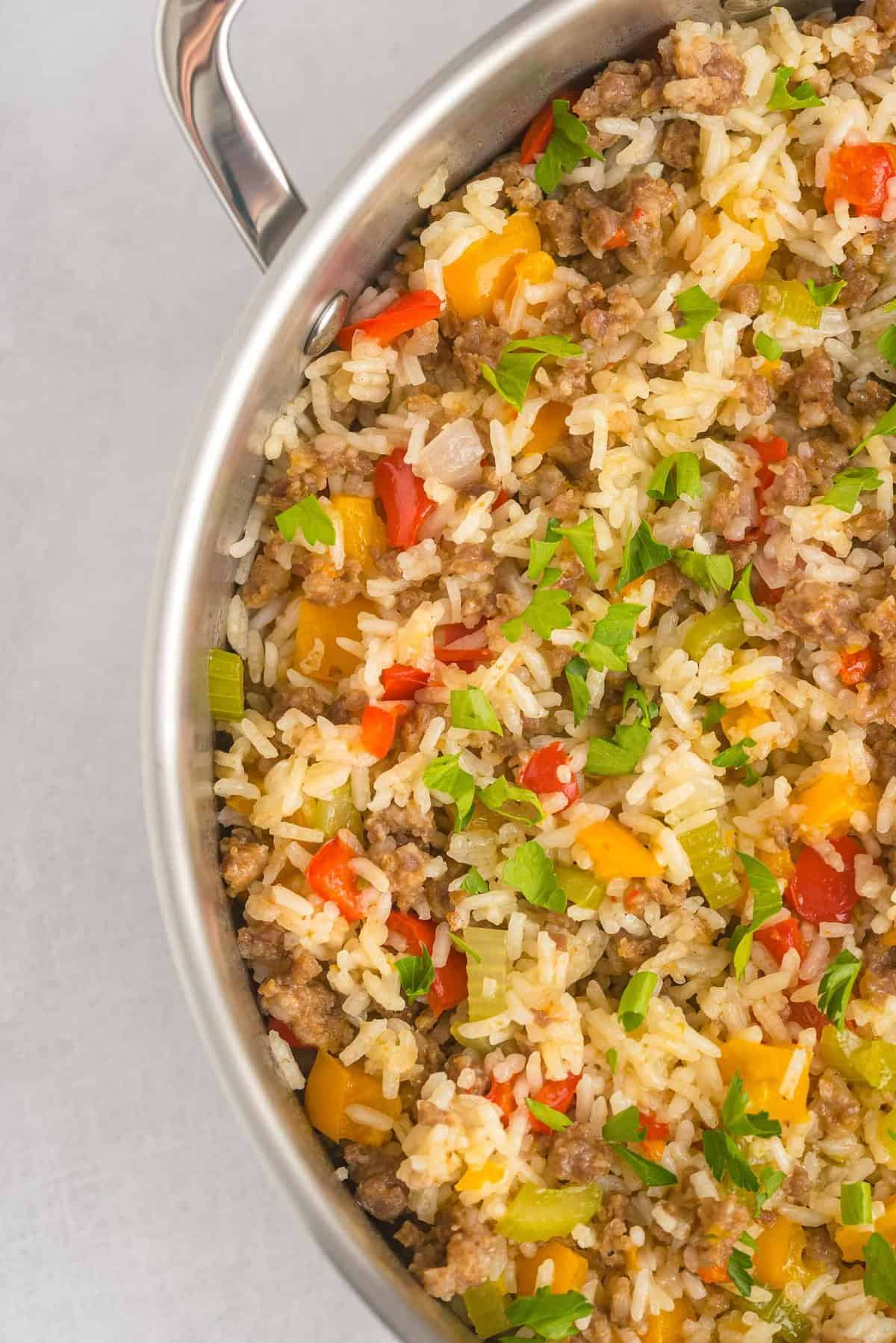 A skillet full of rice and sausage and peppers.