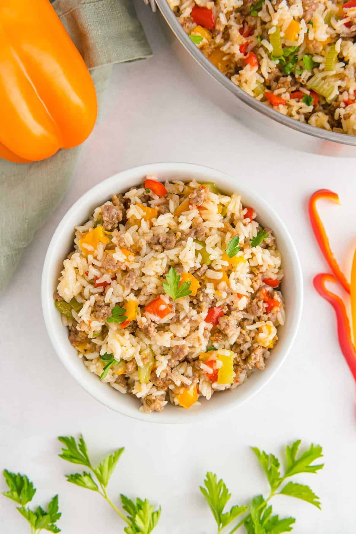 A white bowl filled with ground sausage, peppers, and rice, garnished with parsley.