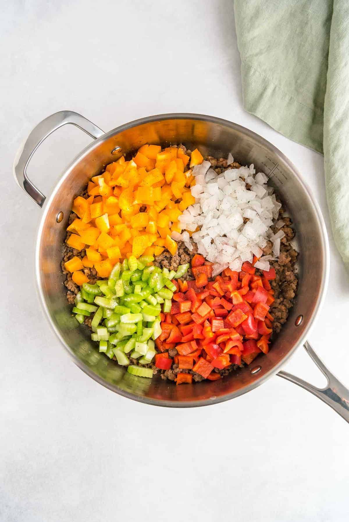 Colorful peppers, onions, and celery in a skillet.