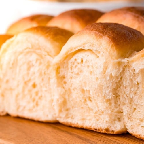 Close up soft fluffy parker house rolls on a wooden board.