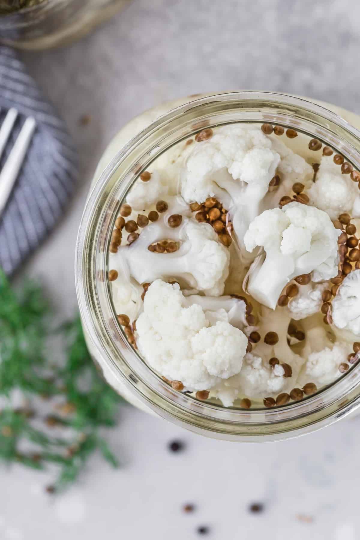 Overhead view of pickled cauliflower in a quart size jar.