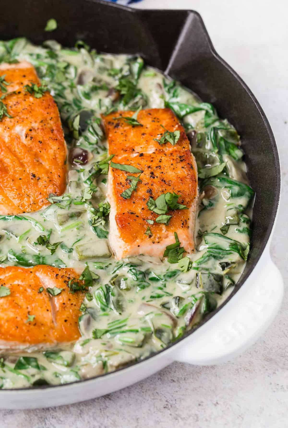 Salmon fillets in a skillet with poblano cream sauce.