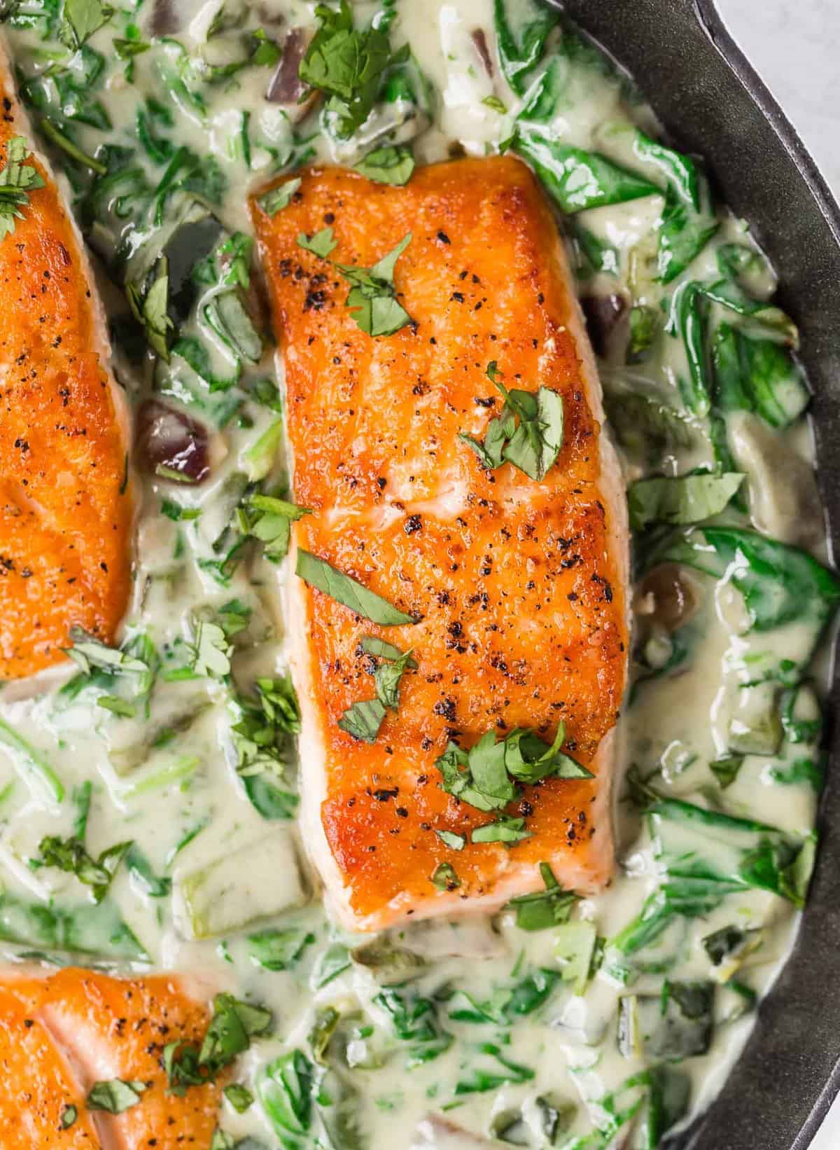 Overhead view of seared salmon in a skillet with poblano cream sauce.