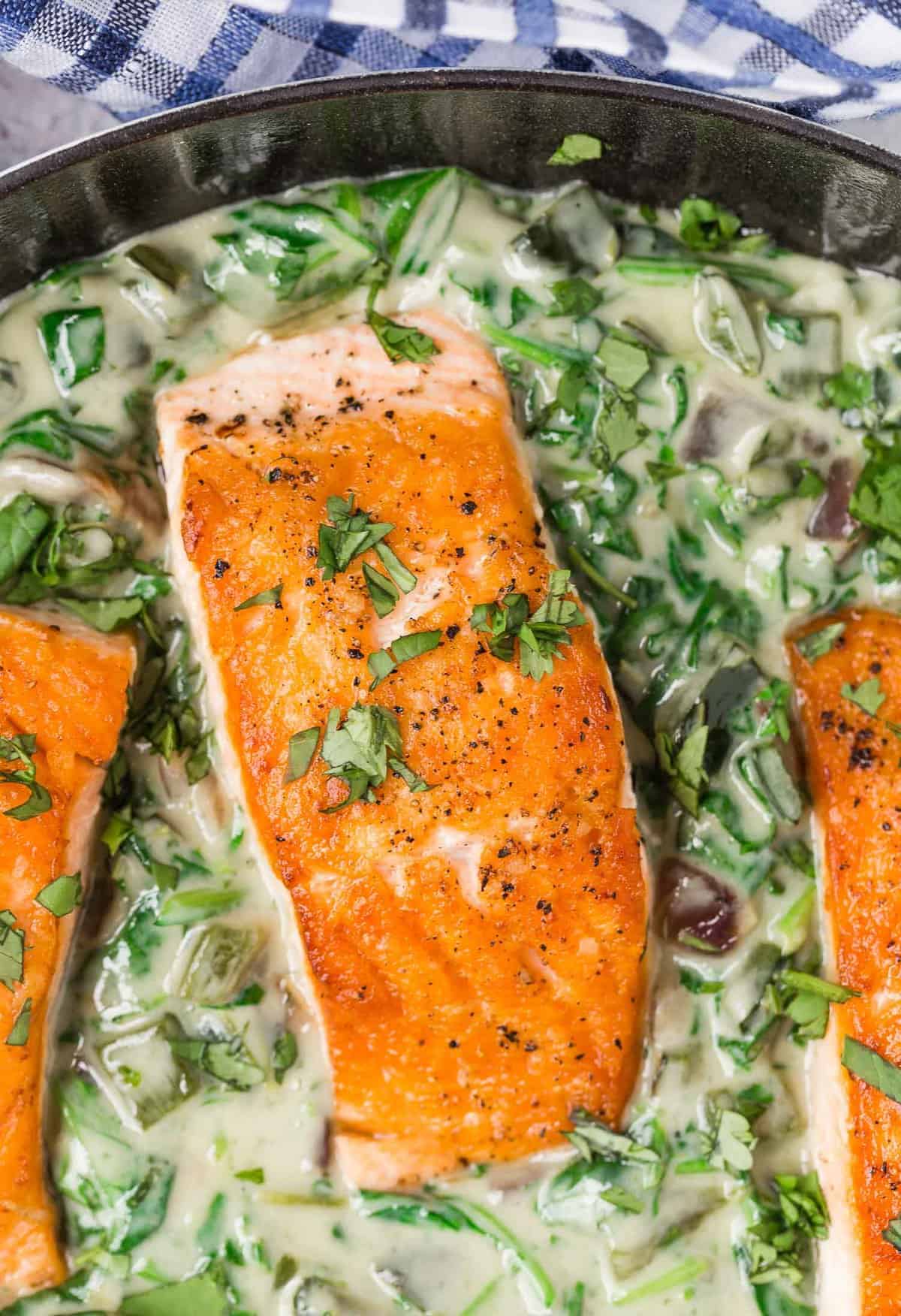 Overhead view of a fillet of seared salmon in a skillet with poblano cream sauce.