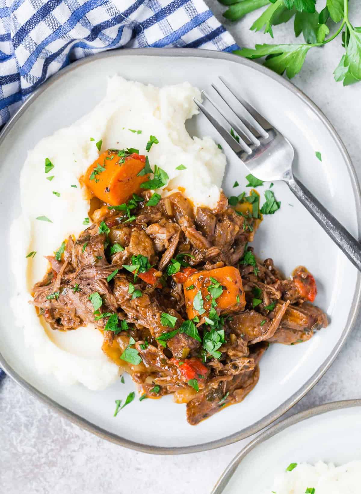 Overhead view of pot roast on top of potatoes.