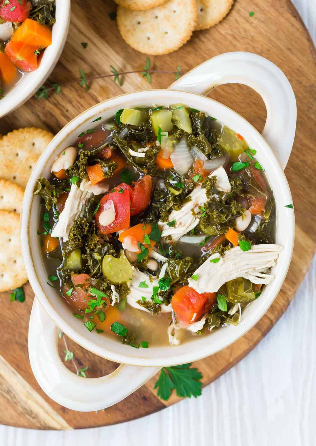 Overhead view of a white two-handled bowl full of colorful healthy soup.