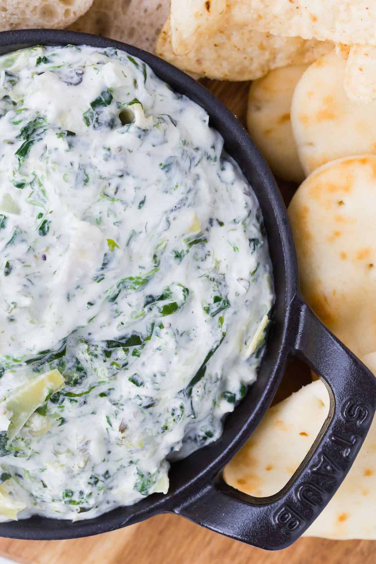 Close up of a creamy dip with spinach and artichoke hearts.