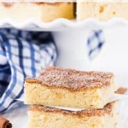 Square cookie bars on a white plate, text overlay reads, "the best snickerdoodle bars, rachelcooks.com"